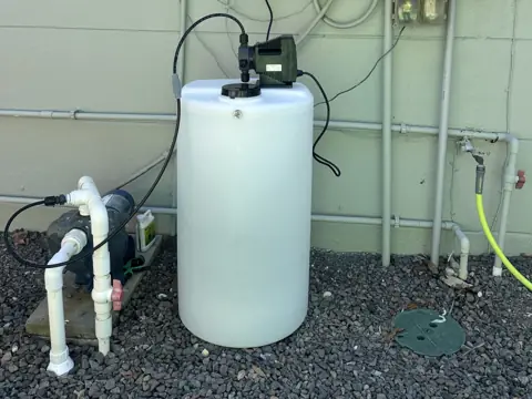 Rust prevention tank and injection pump installed beside a home