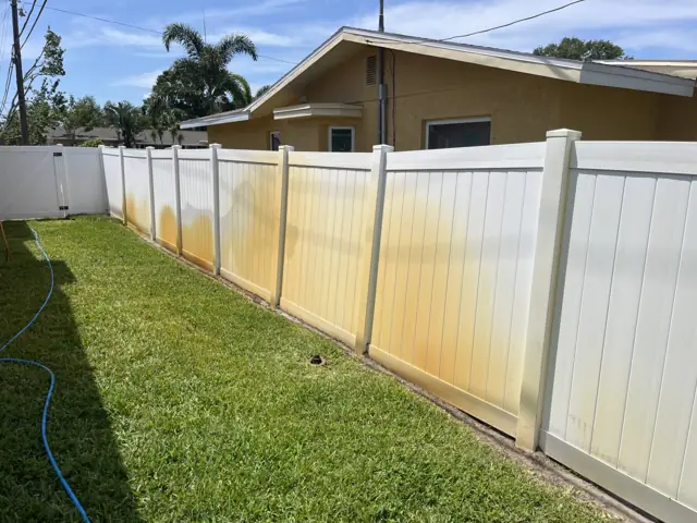 Vinyl fence run with heavy orange irrigation rust, before treatment