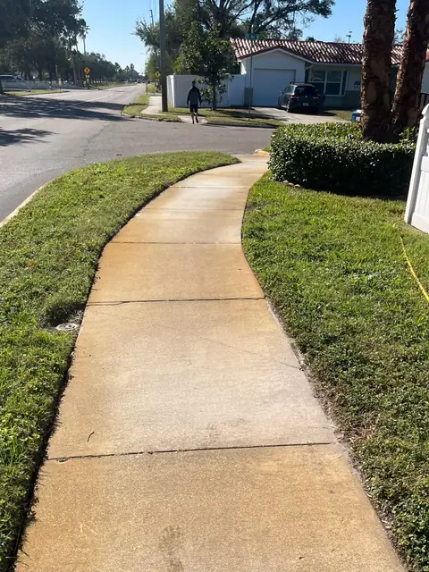 Curved concrete walkway stained orange by sprinkler rust, before