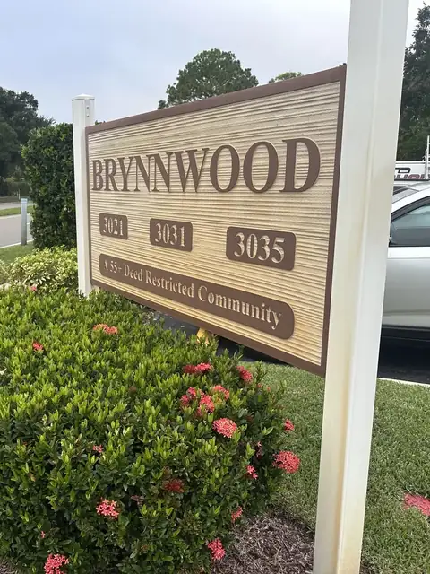 Community entrance sign and white posts discolored orange by irrigation rust, before