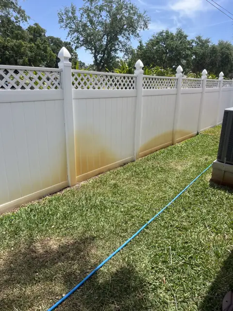 Lattice-top vinyl fence stained orange along the bottom, before