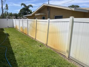 Heavy irrigation rust staining on white vinyl fencing before rust removal